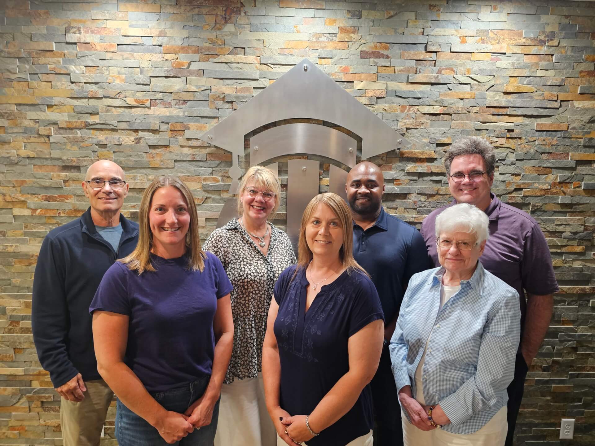 board of directors posed in front of BlueSky logo wall on campus